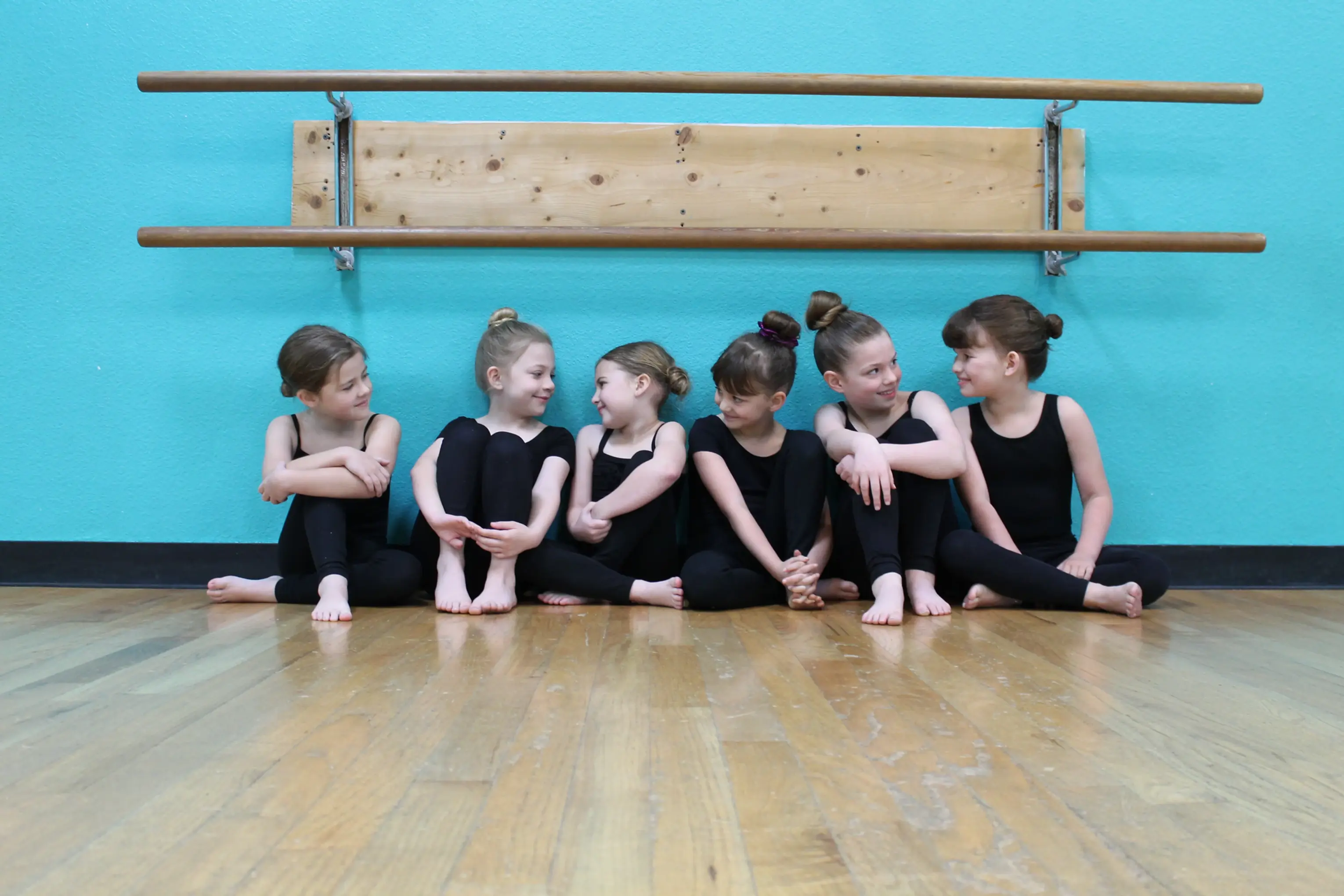 Young Studio 29 dancers smiling together at the barre